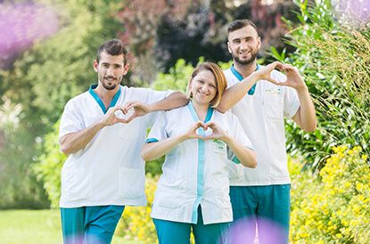 Drei Pflegerinnen und Pfleger formen mit Händen ein Herz