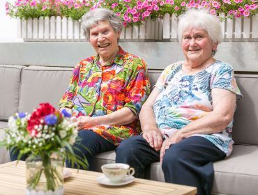 Zwei Bewohnerinnen sitzen mit Kaffee im Garten